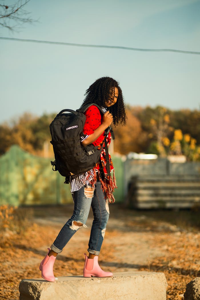 Stylish woman with backpack and pink boots enjoying autumn outdoors.